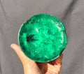Green chatoyant glass boule 1155g - hand held view showing emerald green starburst patterns
