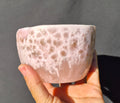 Pink chatoyant glass boule 1472g - hand held view showing honeycomb surface texture