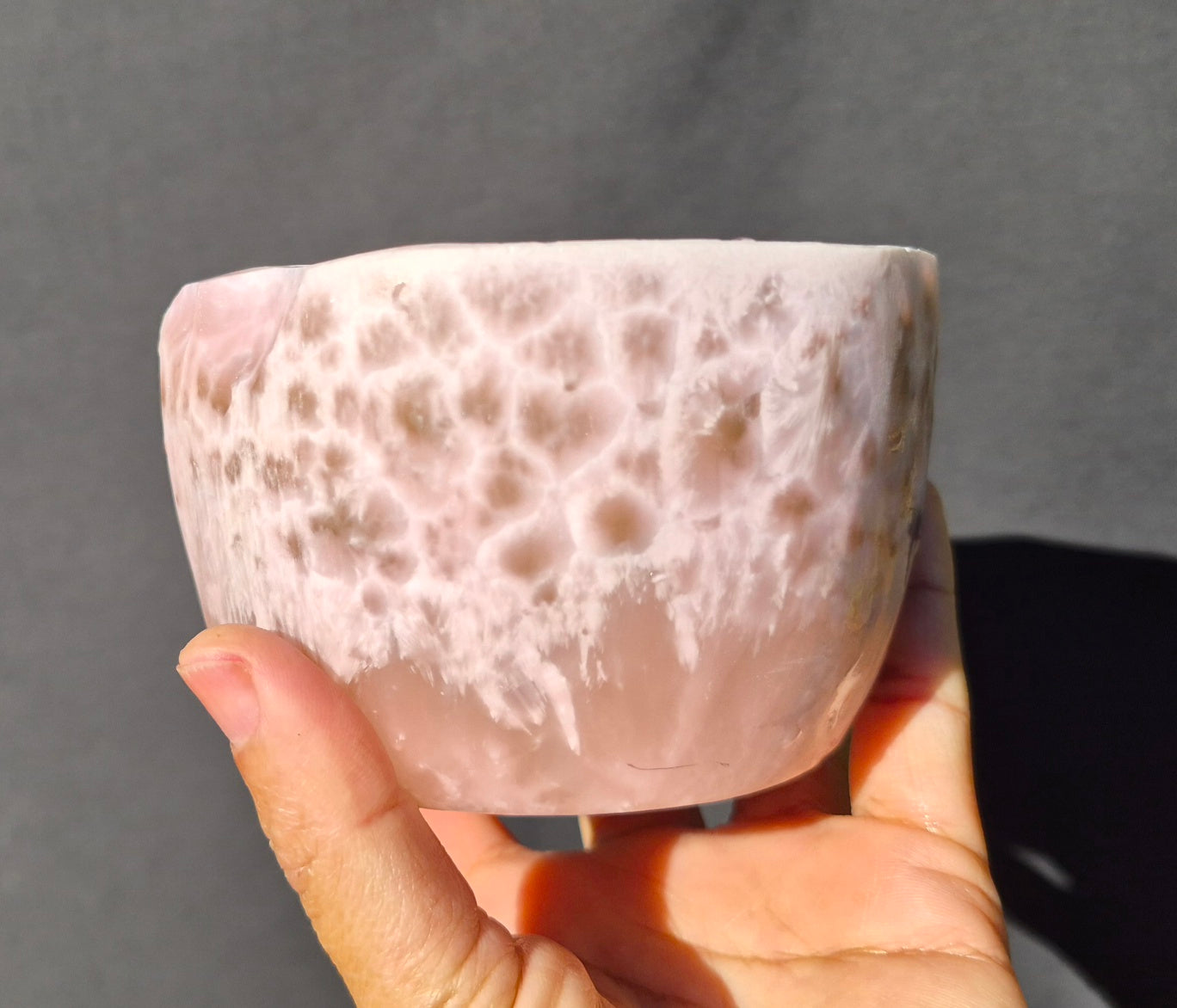 Pink chatoyant glass boule 1472g - hand held view showing honeycomb surface texture