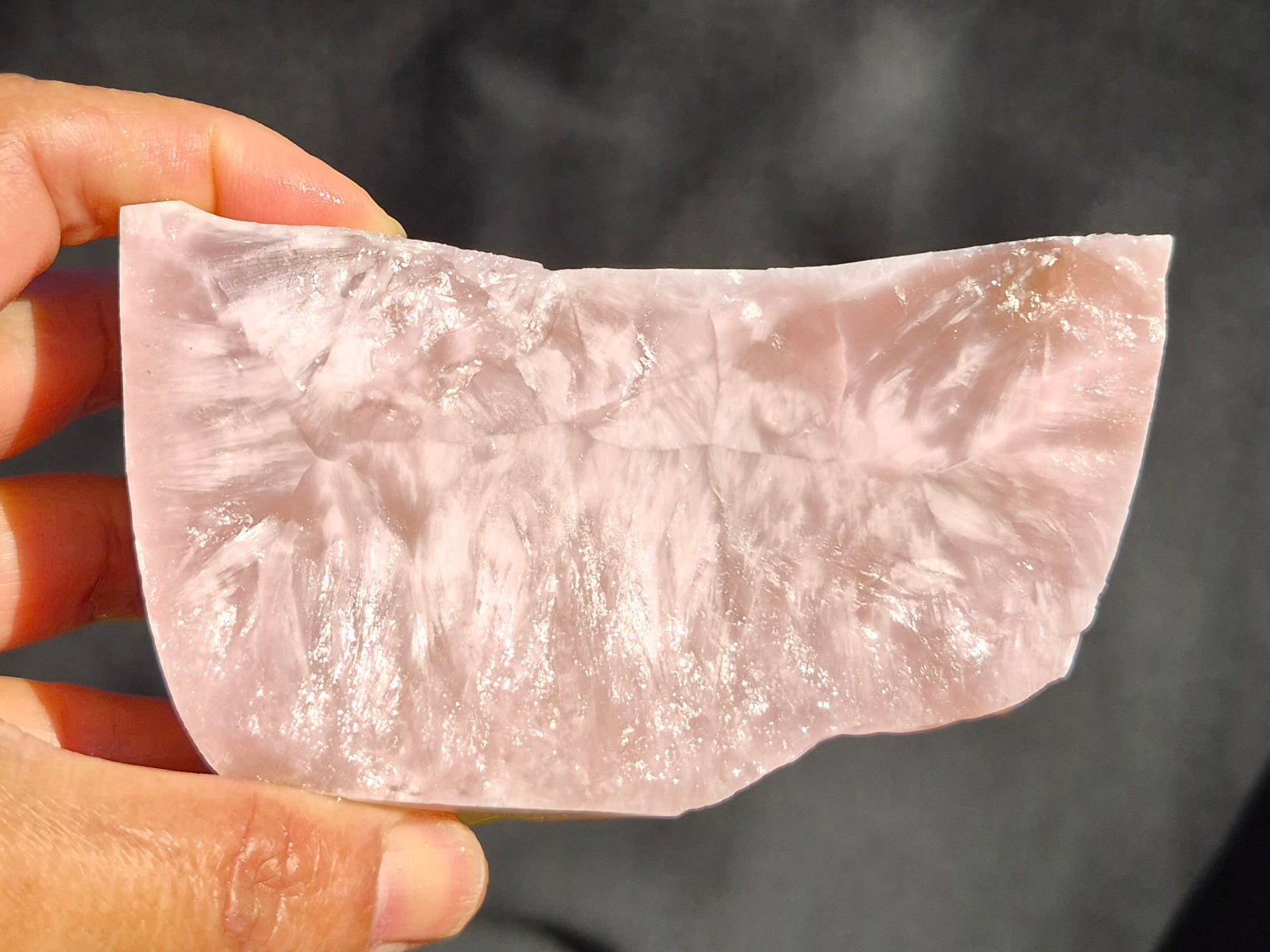 Pink raw chunk 504g – SBSR 120, hand held showing soft rose chatoyancy